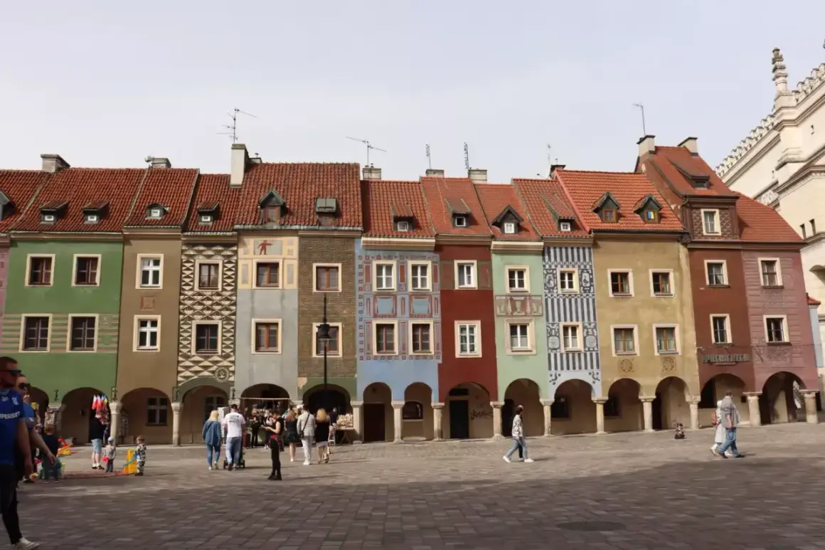 Kolorowe kamieniczki na Starym Rynku w Poznaniu, wspaniałe poznańskie atrakcje. Ludzie spacerują po brukowanym placu.