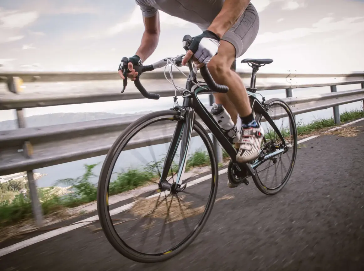 Rowerzysta w rękawiczkach i spodenkach ściga się po drodze. Czy rowerzysta może wyprzedzać z prawej strony? To zależy od przepisów.