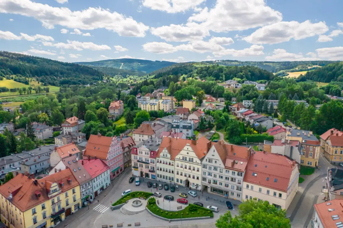Urokliwy rynek w Dusznikach Zdroju, otoczony kolorowymi kamieniczkami, zachęca do odkrywania lokalnych atrakcji.