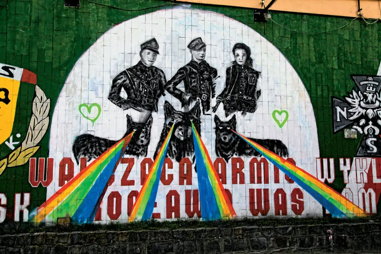 Trzy postacie w mundurach stoją nad trzema wilkami, z których oczu wychodzą tęczowe promienie. To jedno z wielu ciekawych murale w Polsce.
