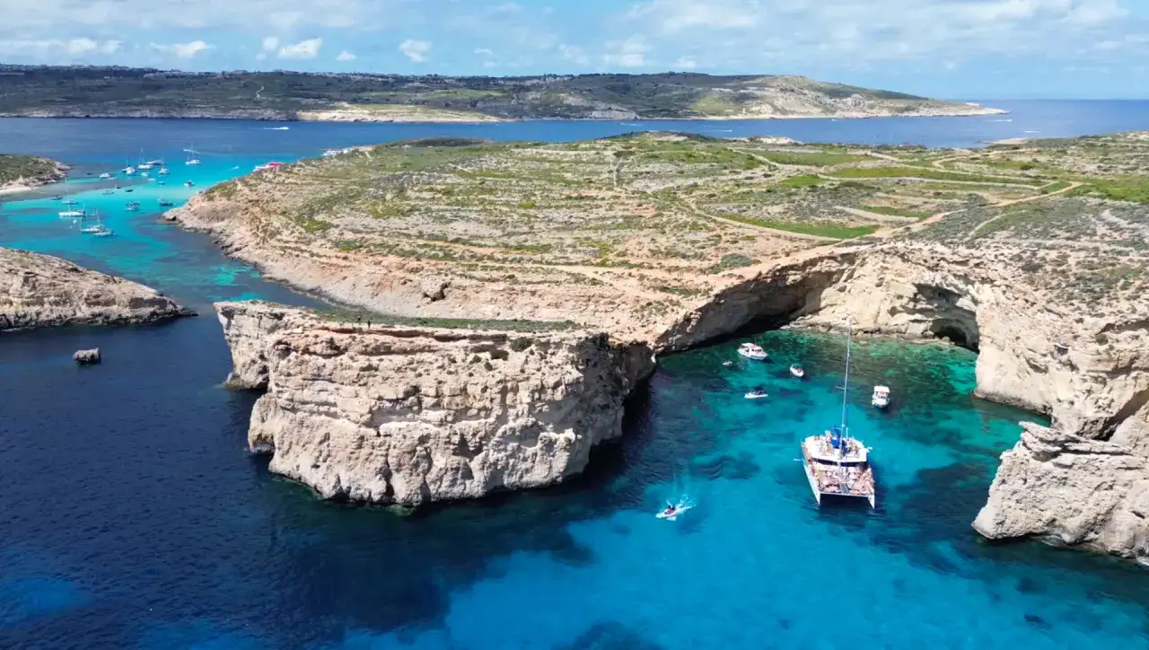 Malta na ile dni? Idealnie na tydzień, by nacieszyć się błękitnymi wodami i skalistymi zatoczkami, jak ta z łodziami i katamaranem.