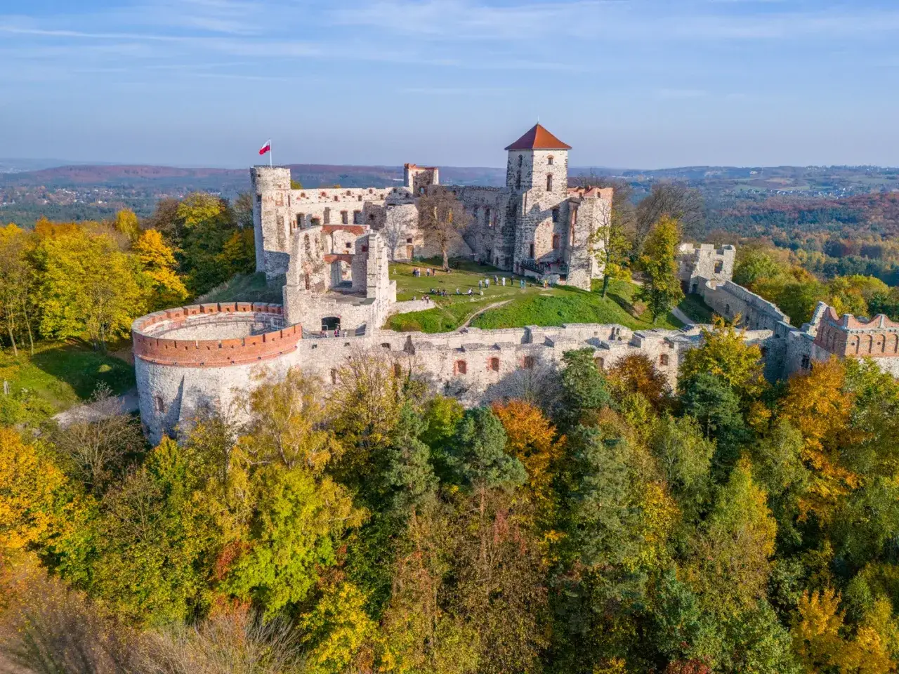 Ruiny zamku na Szlaku Orlich Gniazd, otoczone jesiennymi drzewami w pełnej krasie.