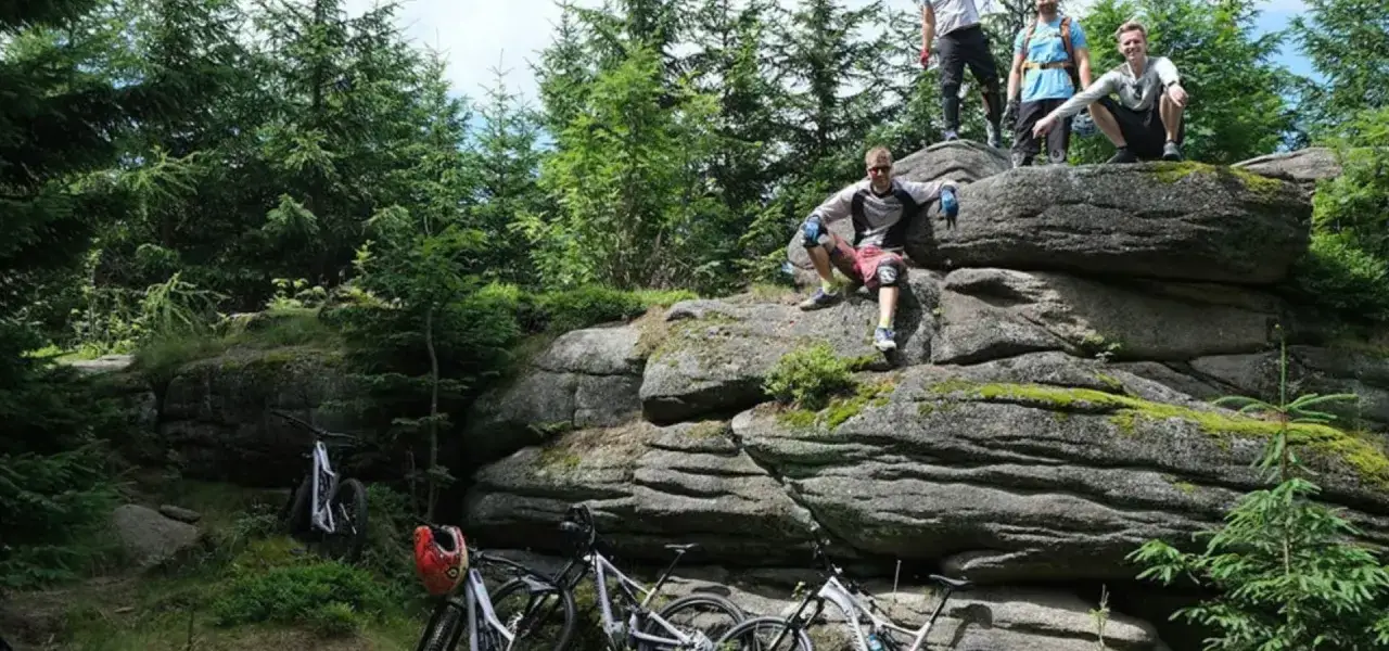 Grupa rowerzystów odpoczywa na skalnych formacjach po zjeździe po trasach rowerowych Karpacz.