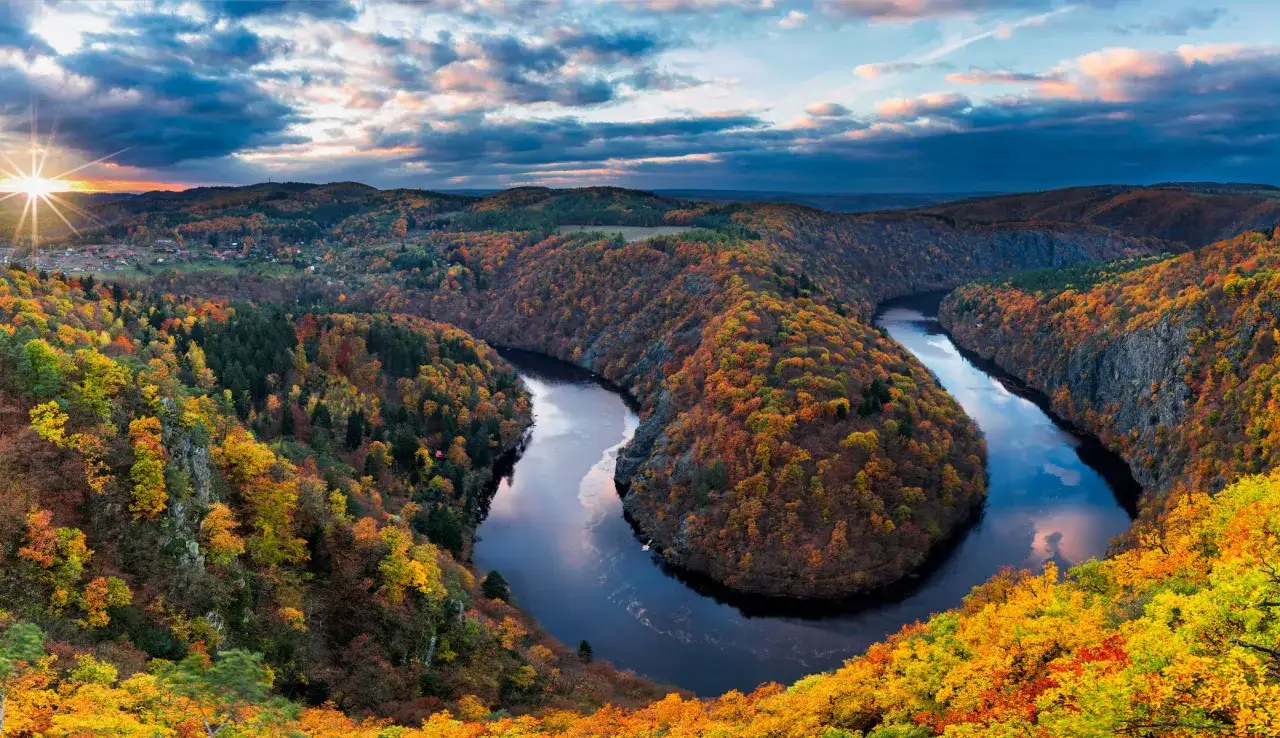 Jesienny krajobraz z meandrującą rzeką i wzgórzami w barwach jesieni. Idealne miejsce na piękne trasy rowerowe Czechy.