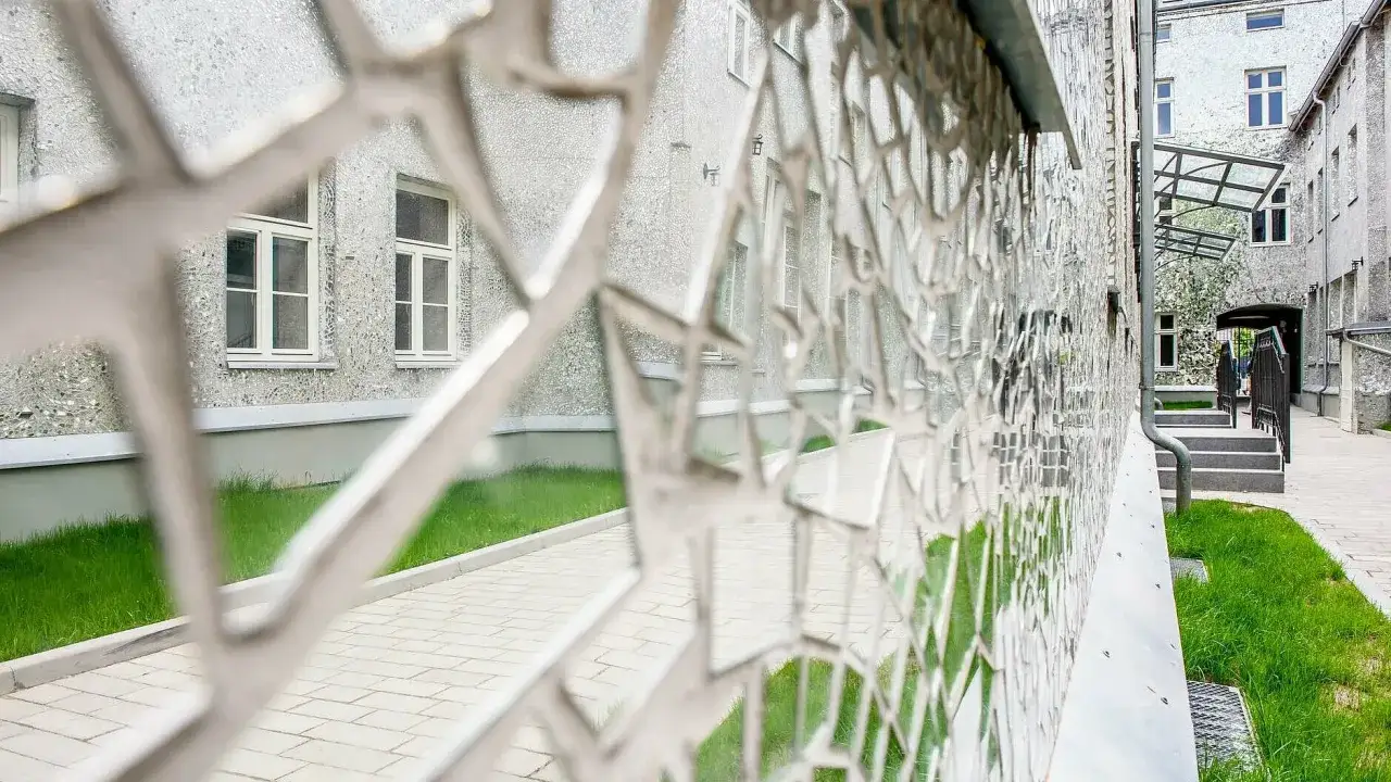 Fasada budynku w Łodzi, pokryta mozaiką, z metalową ażurową balustradą. Atrakcje turystyczne miasta.